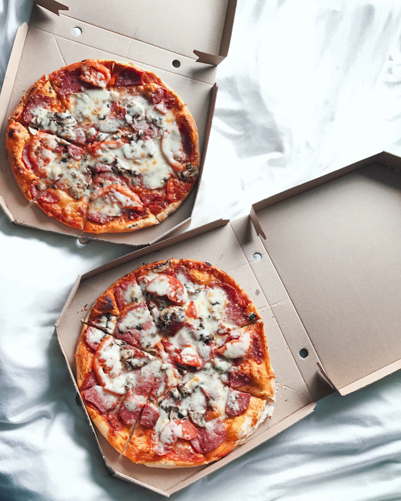 Two pizzas in open cardboard pizza boxes